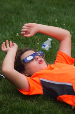 Boy with eclipse glasses looking up